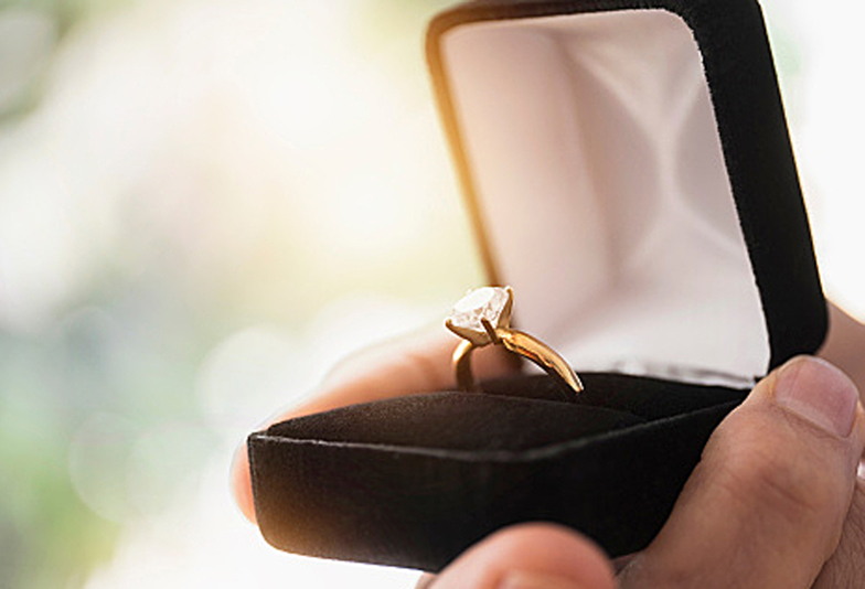 Close up of mans hand holding open box with engagement ring