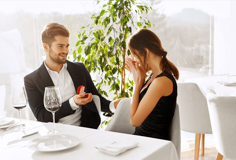 Love. Romantic Couple Relationship. Closeup Of Handsome Man Making Proposal Of Marriage To Beautiful Woman With Engagement Diamond Ring In Luxury Gourmet Restaurant. Wedding, Romance Concept.