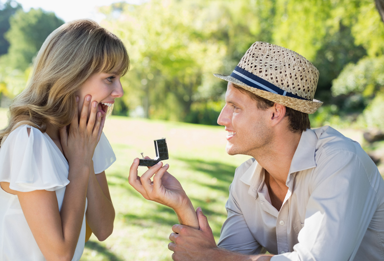 Man surprising his girlfriend with a proposal in the park on a sunny day