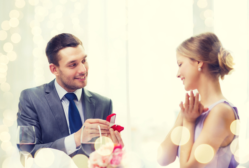 restaurant, couple and holiday concept - smiling man proposing to his girlfriend at restaurant