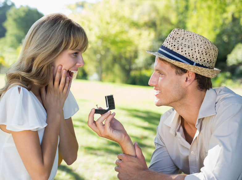 Man surprising his girlfriend with a proposal in the park on a sunny day