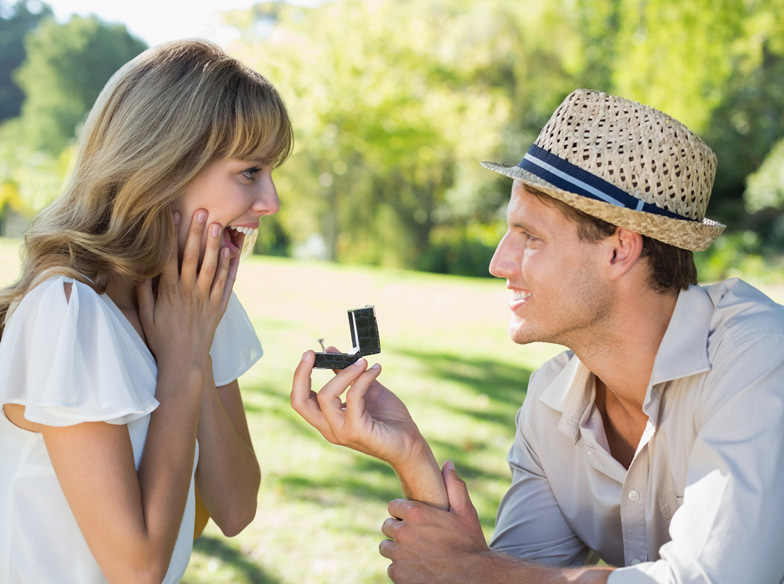 Man surprising his girlfriend with a proposal in the park on a sunny day