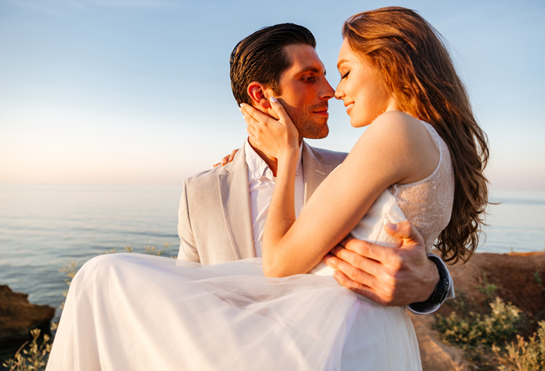 Attractive bride and groom getting married by the beach at sunset