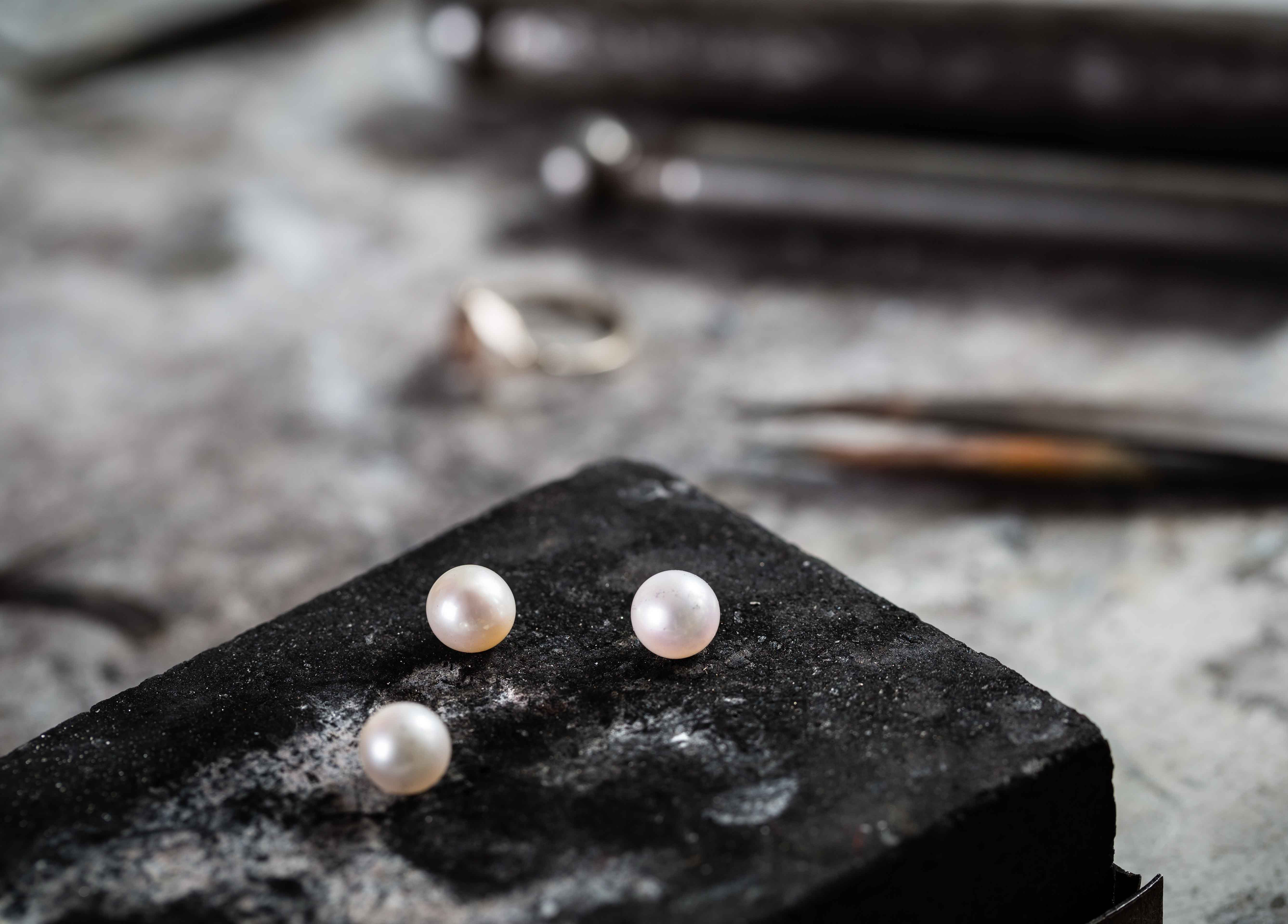 Working desk for craft jewelery making with professional tools and three pearls.