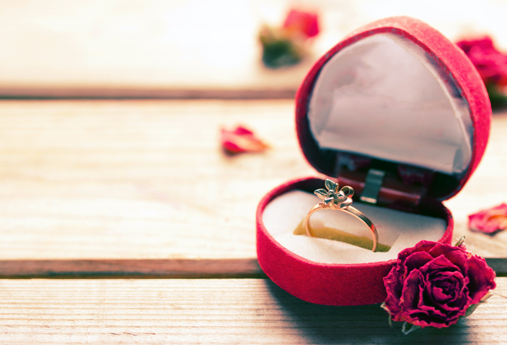 Golden engagement ring in a heart shaped box and roses