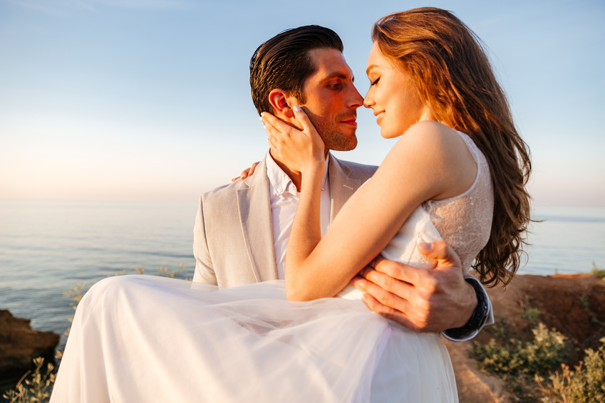Attractive bride and groom getting married by the beach at sunset