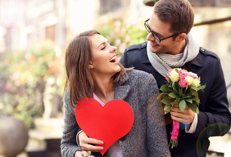 Picture of young man surprising woman with flowers and heart