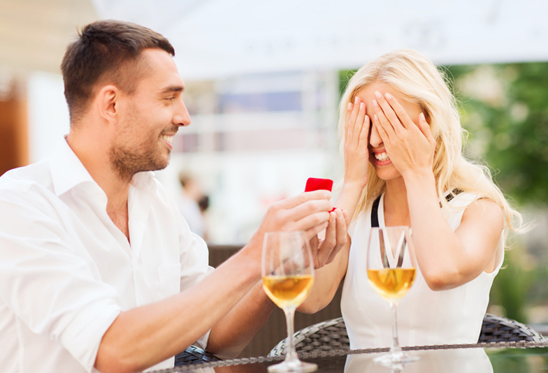 happy couple with engagement ring and wine at cafe