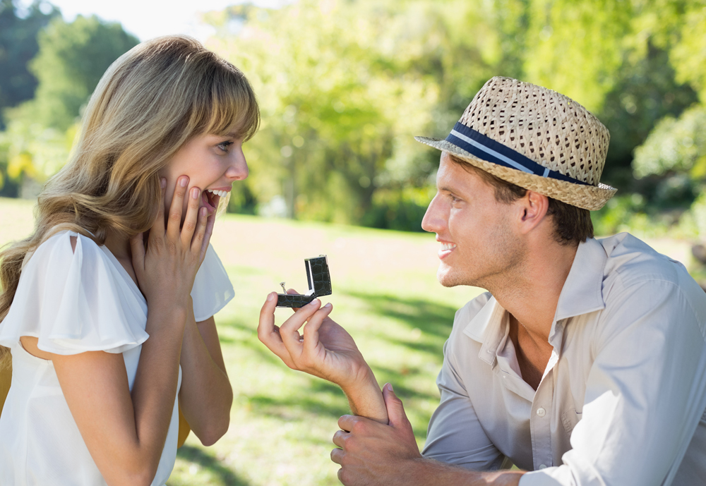 Man surprising his girlfriend with a proposal in the park on a sunny day