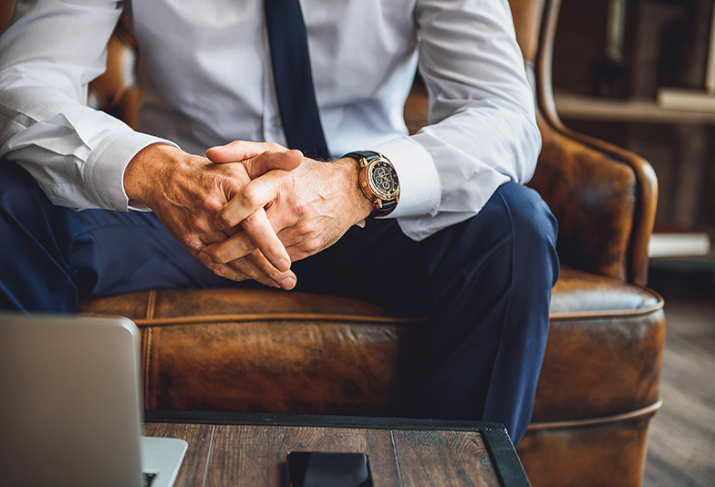 Focus on hands of businessperson. He is sitting on couch