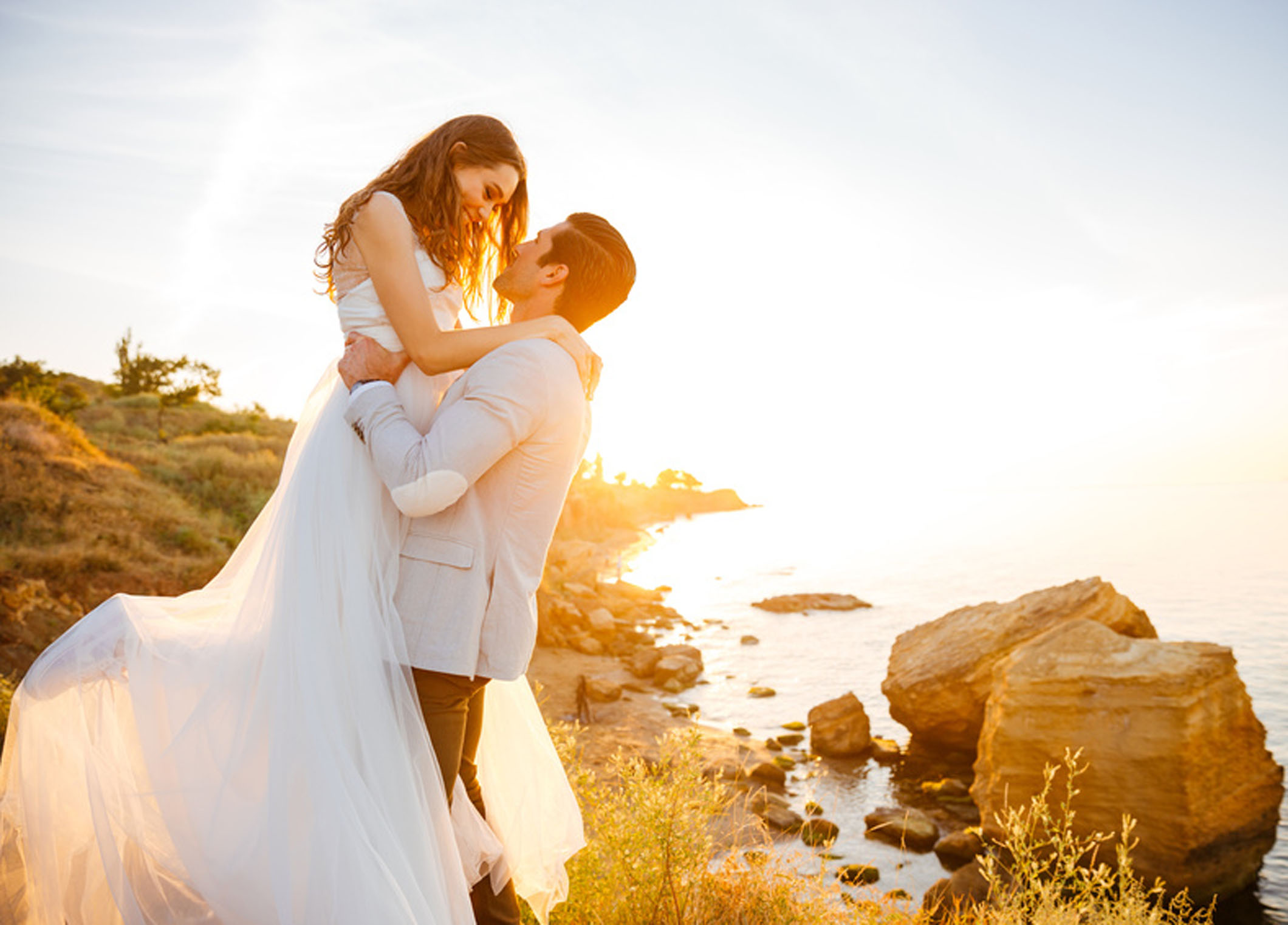 Attractive bride and groom getting married by the beach at sunset