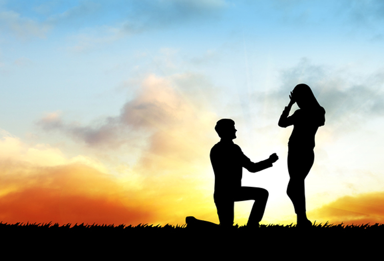 Silhouette couple on the sunset and man makes a proposal