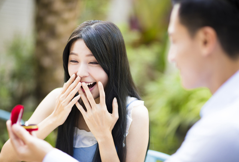 Man proposing to girlfriend offering engagement ring in restaurant