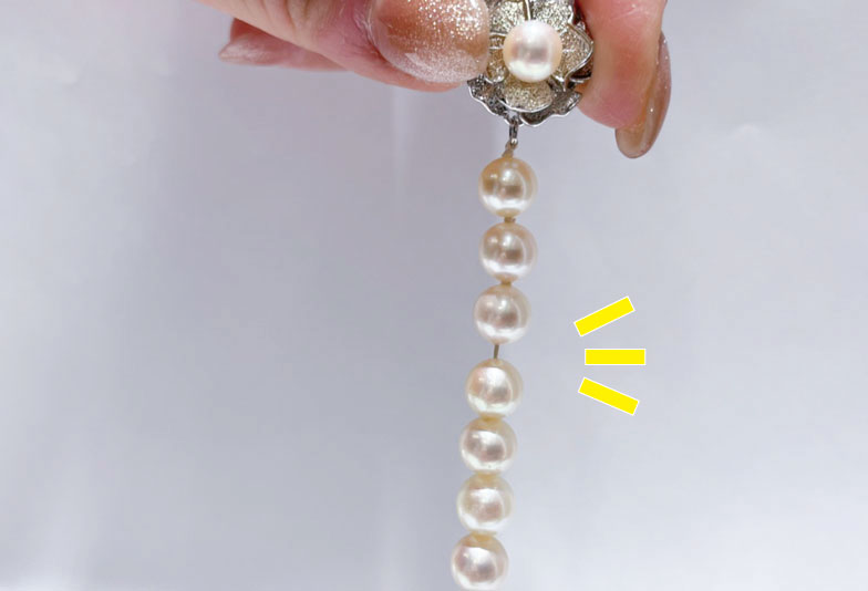 留め具を持って下に垂らすと、真珠の間に隙間ができます。